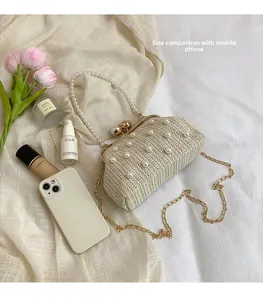 Straw woven bag detail showing pearl strap and metal chain next to a mobile phone