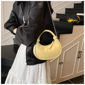 Detail of yellow crescent shoulder bag with knotted handle and silver chain strap