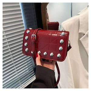 Burgundy patent leather crossbody bag with silver studs and geometric stitching details