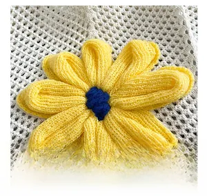 Macro detail of hand-knitted yellow flower ornament on textured straw tote bag