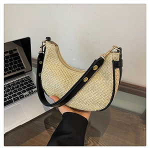 Detail of straw woven crescent bag with black leather trim and gold metal rivets