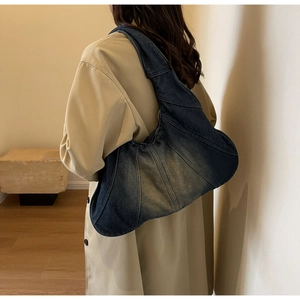 Model wearing a vintage deep blue denim hobo bag with patchwork stitching and retro wash