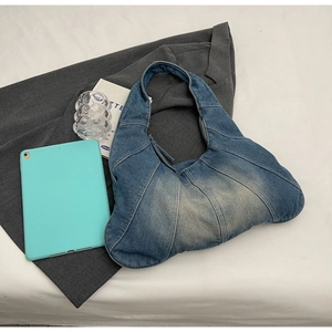 Detail of vintage denim patchwork shoulder bag with visible stitching on grey fabric