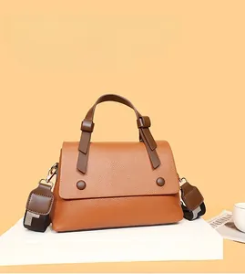 Detail of a brown lychee pattern leather handbag with wide two-tone shoulder strap