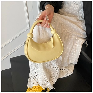 Close-up of bright yellow crescent handbag with knot detail and smooth leather finish