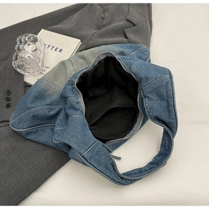 Detail of blue denim hobo bag interior featuring black fabric lining and zippered pocket