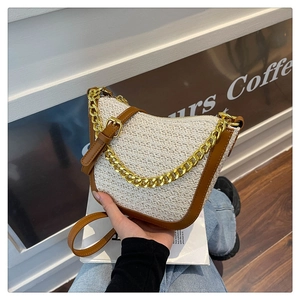 Detail of woven crescent bag featuring brown leather trim and chunky gold chain strap