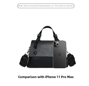 Detail view of the black pebble leather texture and wide shoulder strap on the handbag