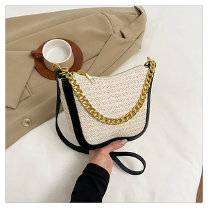 Detail of woven straw shoulder bag with black leather piping and gold chain strap