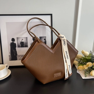 Sac cabas plissé marron foncé avec ouverture en V et ruban décoratif sur décor chaud