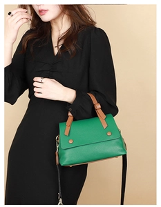 Detail of green pebble leather crossbody bag with wide strap and brown trim detail