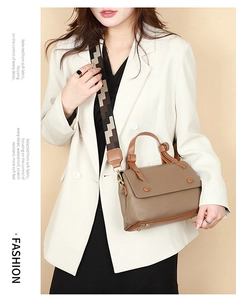 Brown textured leather handbag with a wide geometric patterned shoulder strap and gold hardware