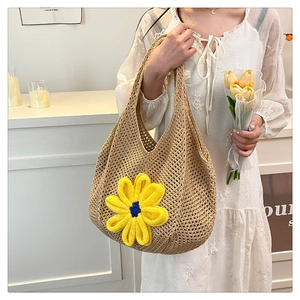Detail of beige crochet tote bag featuring a yellow knitted flower and hollow weave texture