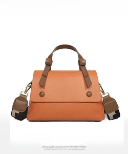 Close-up of orange litchi grain leather handbag with woven strap and gold hardware