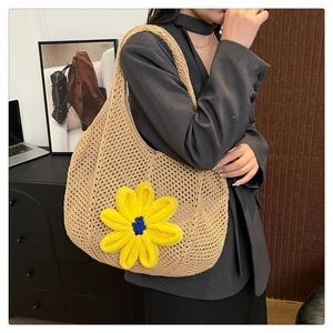 Detail of beige straw tote bag featuring a large yellow flower with a blue center