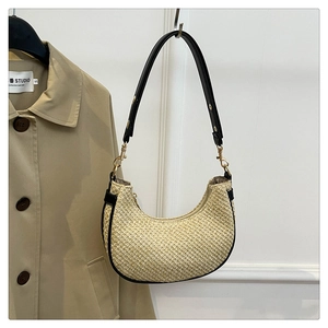 Detail of minimalist beige woven hobo bag with black leather trim and gold metal hooks