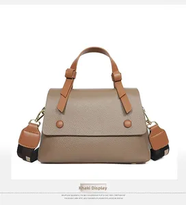 Detail of khaki leather handbag with wide woven strap and litchi grain texture