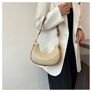 Detail of hobo bag showing straw texture and brown leather strap with gold hardware