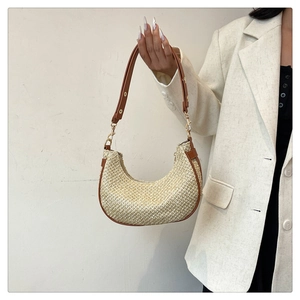 Detail of straw hobo bag with brown leather trim and adjustable gold buckle
