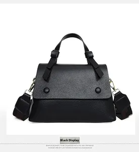 Detail of black pebbled leather handbag with wide shoulder strap and gold hardware
