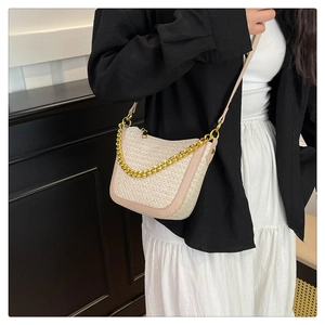 Detail of woven cream fabric bag with gold chain and leather trim on model