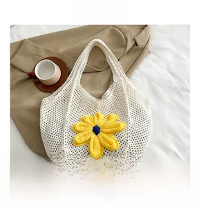 Detail of white crochet tote bag with a yellow knitted flower on soft white bedding