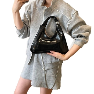 Elegante borsa a mezzaluna in pelle verniciata nera con sfere d'argento e catena