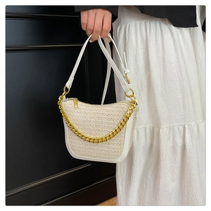 Detail of woven texture handbag with gold metal chain and white leather trim