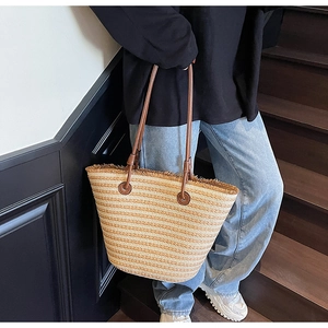 Detail of striped woven tote bag with fringe edge and dark brown leather handles