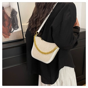 Detail of beige woven baguette bag with white leather trim and gold chunky chain strap