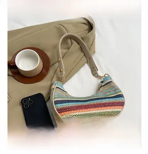 Detailed close-up of striped woven hobo bag with leather strap and golden hardware