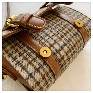 Detail shot of the houndstooth fabric textures and golden magnetic buckles on bag