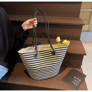 Detail of striped woven tote bag featuring frayed edges and slim shoulder straps