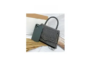 Mini black handbag with sparkling silver rhinestones shown next to a smartphone for scale
