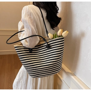 Detail of striped woven tote bag with fringe edge and slim leather shoulder straps
