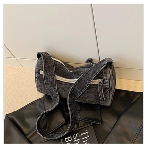 Détail du sac cylindre en jean délavé gris avec fermeture éclair blanche et bandoulière