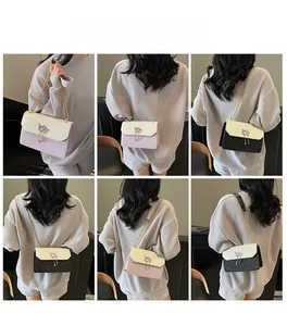 Modèle portant un sac bandoulière chat avec chaîne diamantée et rabat en patchwork