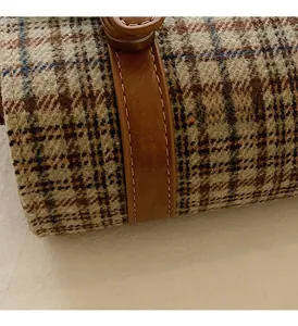 Close-up of houndstooth fabric texture with brown leather trim and precision stitching