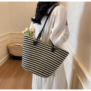 Detail of black and white striped woven tote bag with leather strap and fringe trim