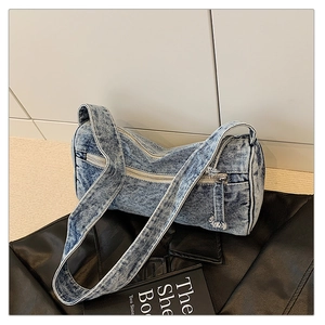 Gros plan détaillé d'un sac cylindrique en denim délavé avec une fermeture éclair en métal