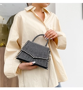 Detail of black envelope handbag with silver rhinestones and metal ball chain