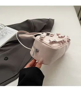 Detail of light pink patent leather mini bowling bag with decorative 3D bows and silver zipper