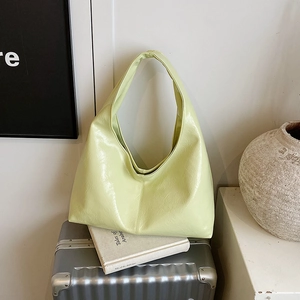 Sac fourre-tout minimaliste vert avocat en cuir verni sur une valise vintage argentée