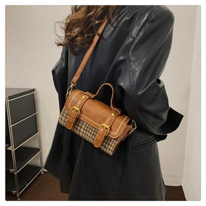 Detail of houndcheck patterned handbag with brown leather trim and golden buckle detail