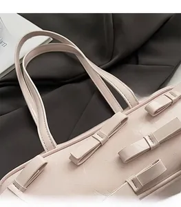 Detail of pink faux leather bag with bow ornaments and double shoulder straps