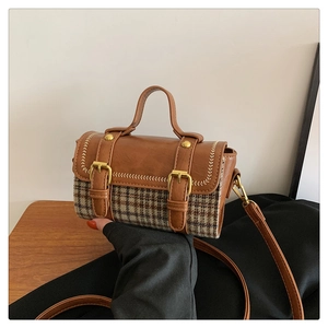 Detail view of houndstooth crossbody bag with gold buckles and brown leather trim