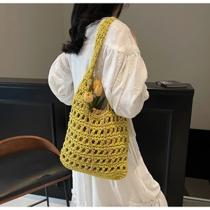 Detail of yellow hollow out woven tote bag with inner drawstring pouch on female model