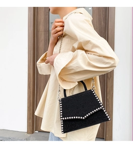 Detail of a black rhinestone crossbody bag with a silver chain and luxury diamond trim