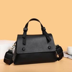 Black lychee textured tote bag with wide strap and gold hardware on warm aesthetic background