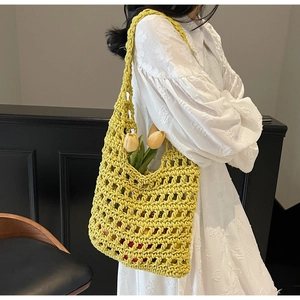 Close-up of bright yellow hand-woven hollow tote bag with intricate mesh detail and floral decor